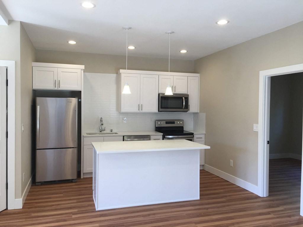 a kitchen with a white island and a stainless steel refrigerator