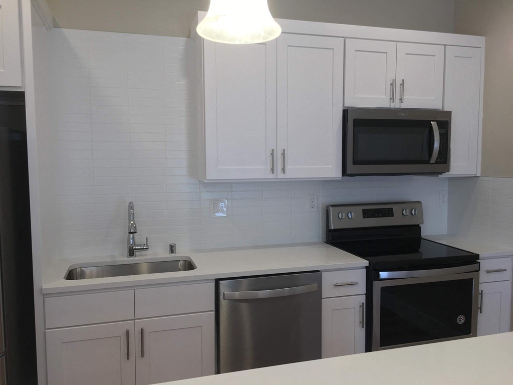 a kitchen with white cabinets and black appliances and a sink