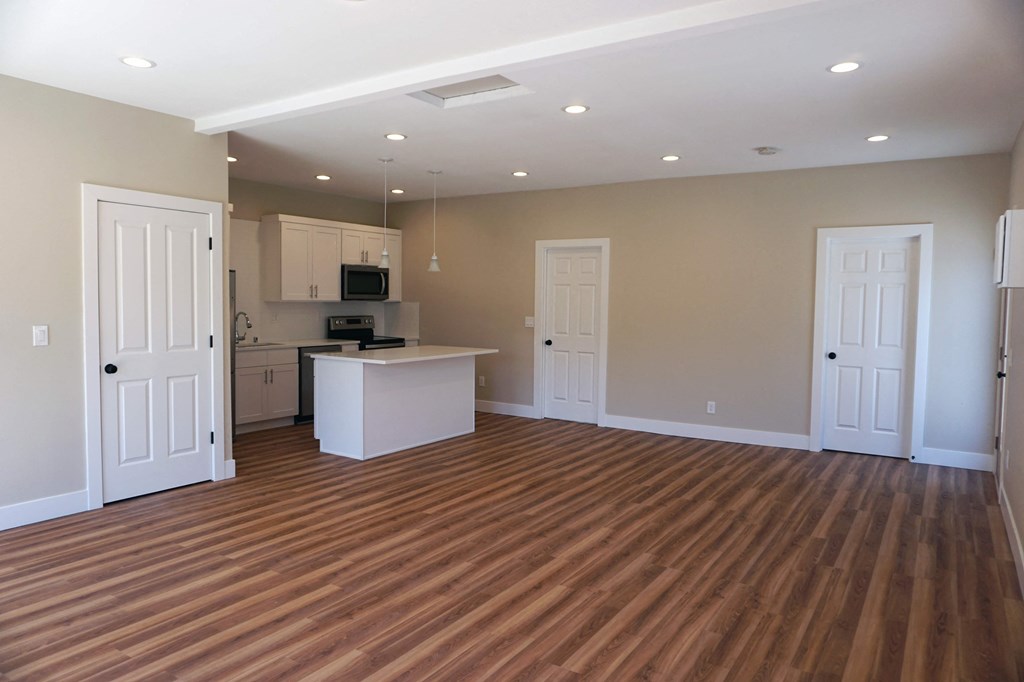 an empty living room and kitchen with wood flooring