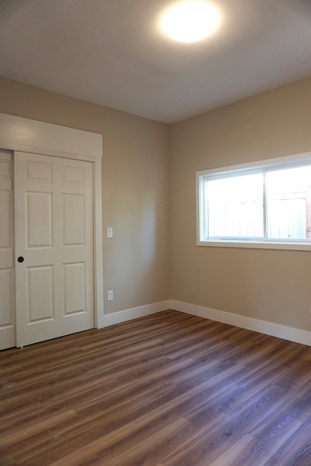 an empty living room with wooden floors and a white door