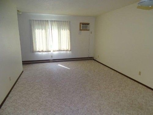 an empty living room with a window and white walls