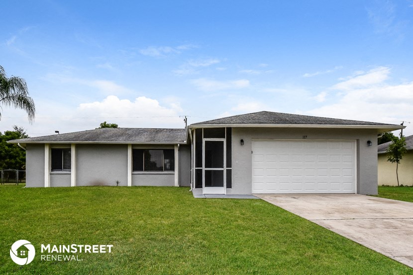 a small white house with a lawn and a driveway