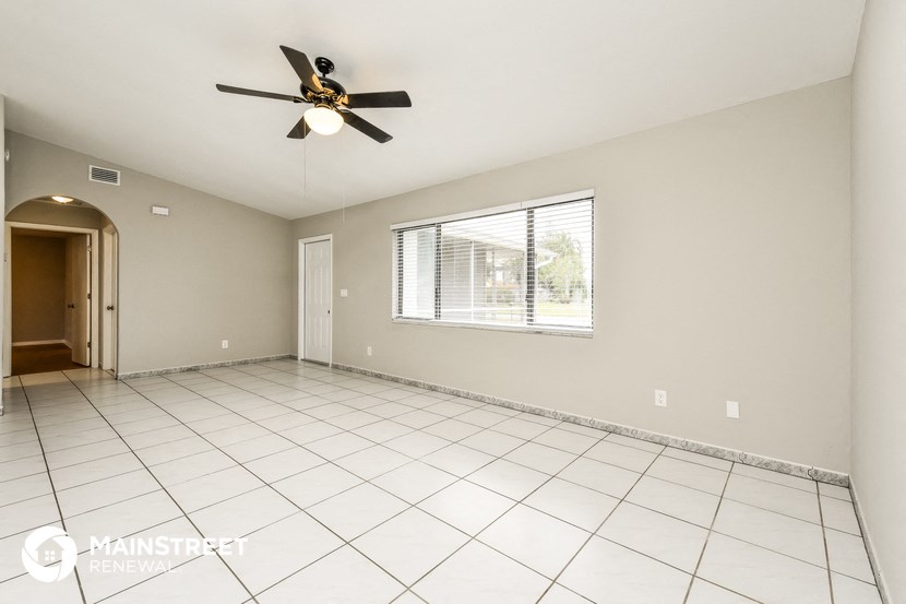 an empty living room with a ceiling fan and tiled floor