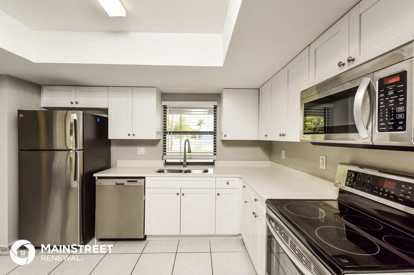 a white kitchen with stainless steel appliances and white cabinets