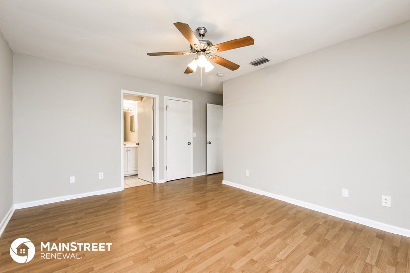 the living room and dining room with wood flooring and a ceiling fan