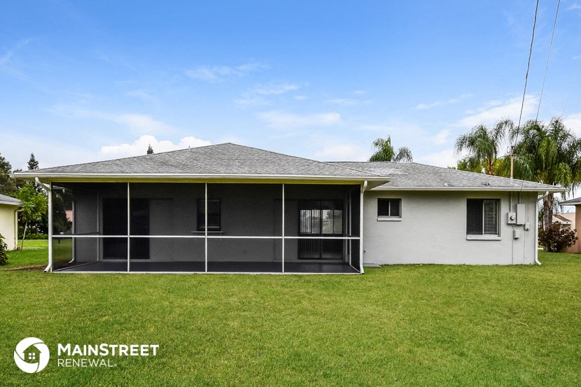 a house with a screened in porch and a grass yard