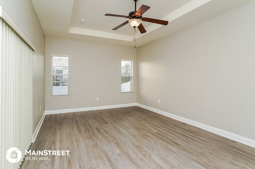 the spacious living room with hardwood floors and a ceiling fan