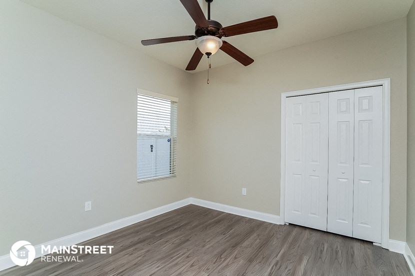 an empty bedroom with a ceiling fan and a closet