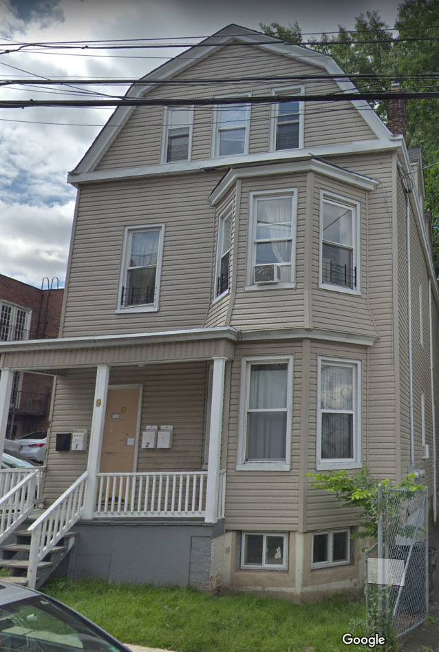 the front of a tan house with white stairs