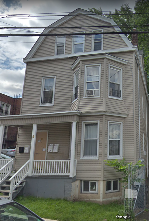 the front of a tan house with white stairs