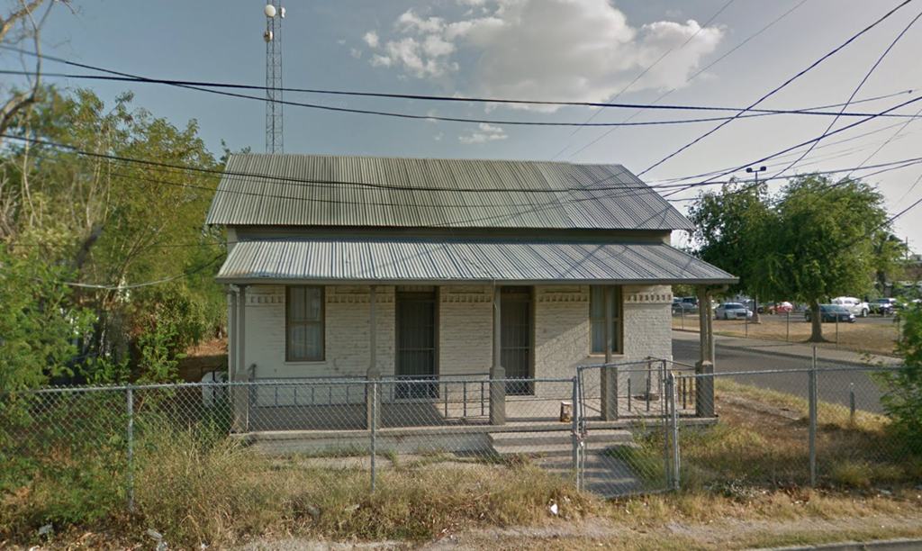 an old building with a metal roof on the side of a road