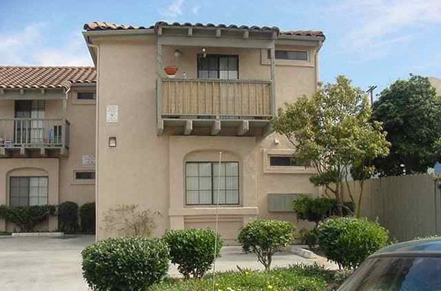 an apartment building with a balcony and a car parked in front