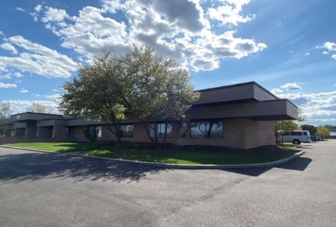A building with a parking lot in front of it on a sunny day.