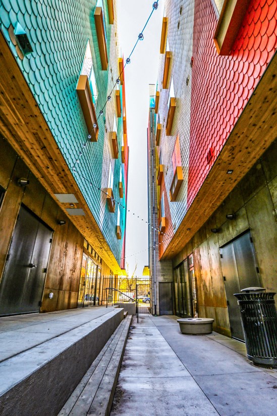 a narrow alleyway between two buildings with colorful facade and a trash can
