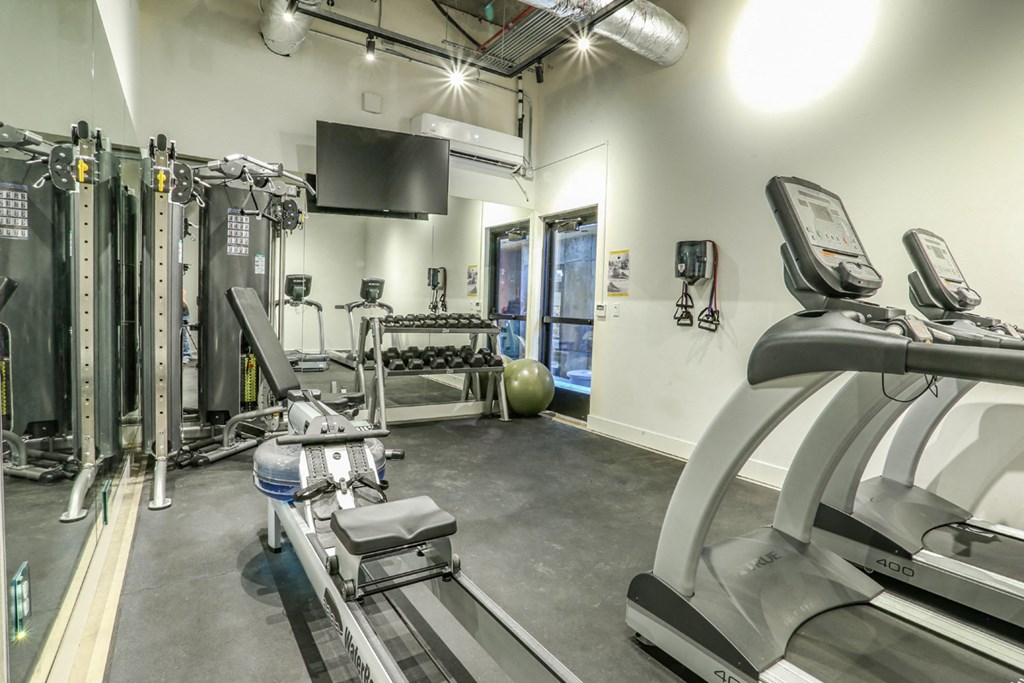a gym with treadmills and other exercise equipment in the corner of a room