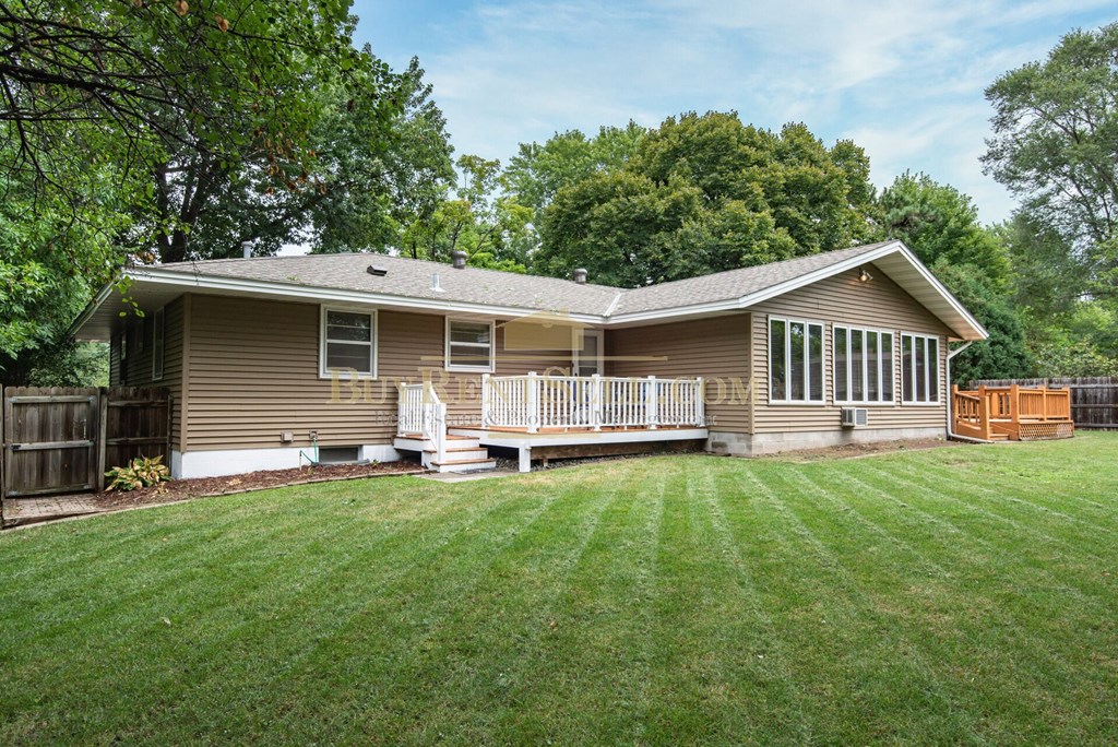 a brown house with a yard and a deck