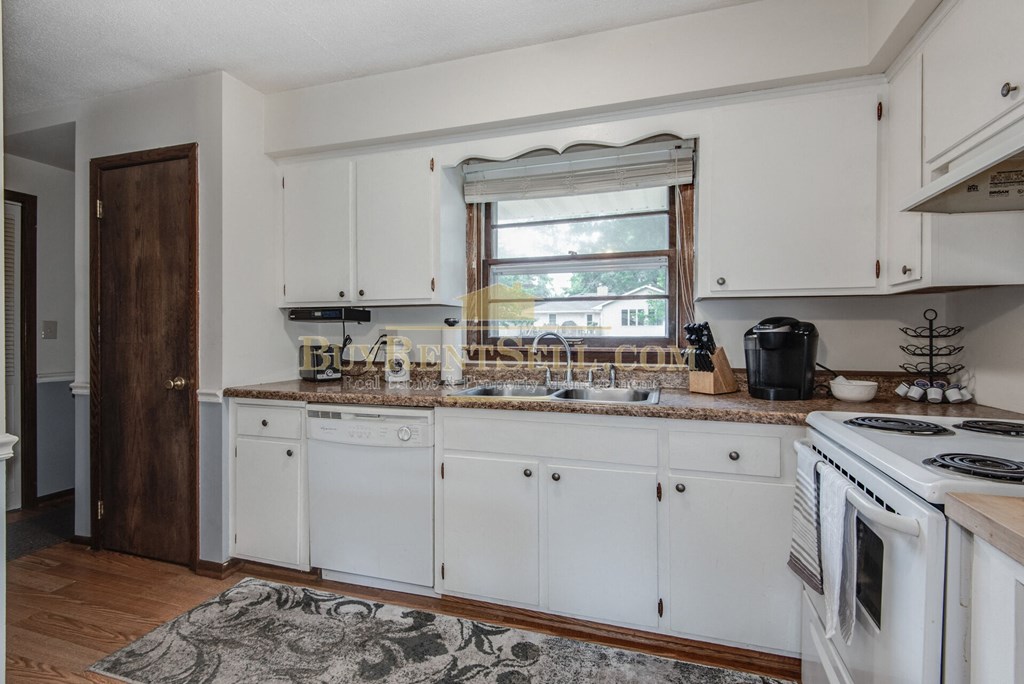 a kitchen with white cabinets and a stove and a window