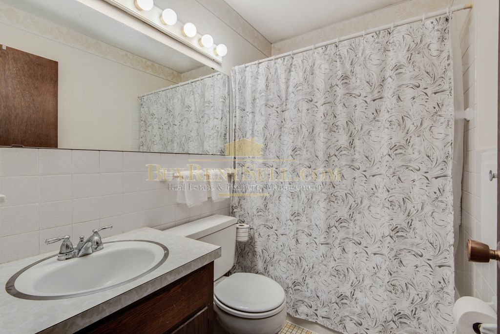 a bathroom with a shower curtain and a sink and a toilet