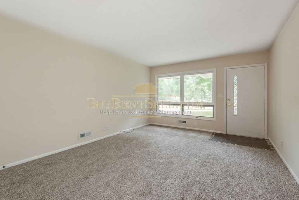a bedroom with carpet and a door to a balcony