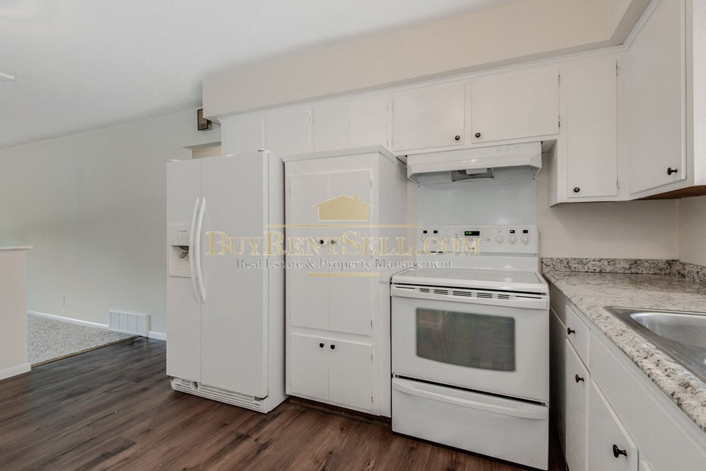 a kitchen with white cabinets and white appliances and a wood floor