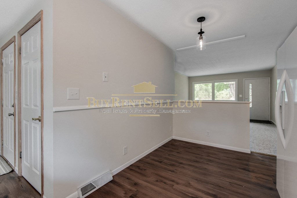 a room with a white wall and a white door and a wood floor