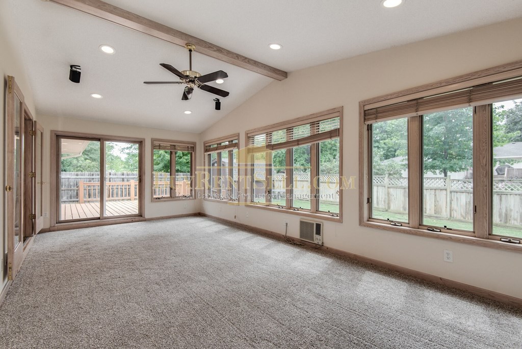 an empty living room with windows and a ceiling fan