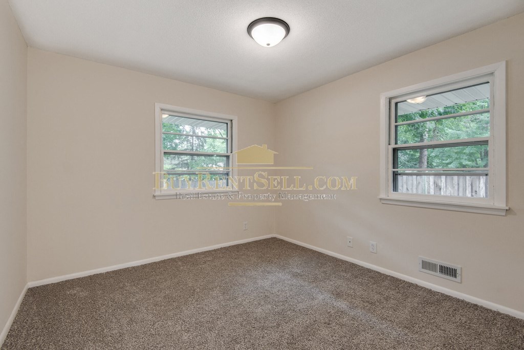 a bedroom with a carpeted floor and two windows