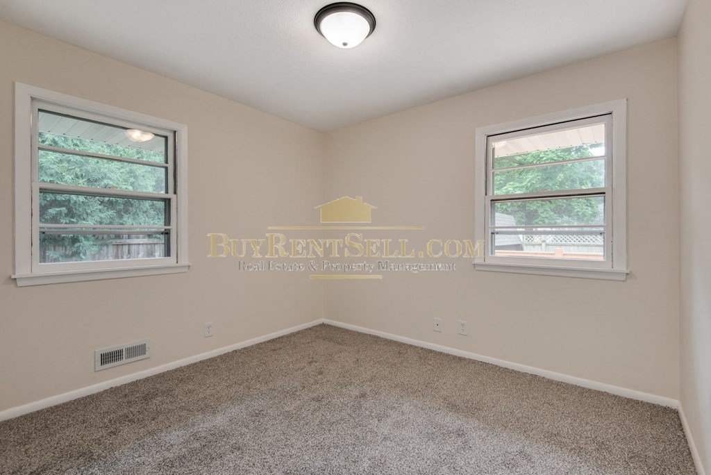 a bedroom with a carpeted floor and two windows
