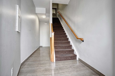 a flight of stairs with a wooden railing and white walls