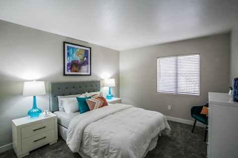 A bedroom with a bed, nightstand, and chair.