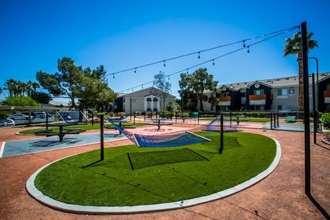 A playground with a blue slide and a green lawn.
