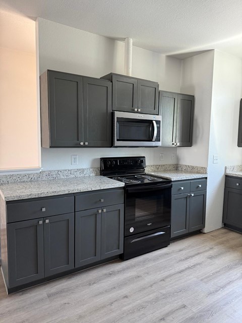 A kitchen with black cabinets and a granite countertop.