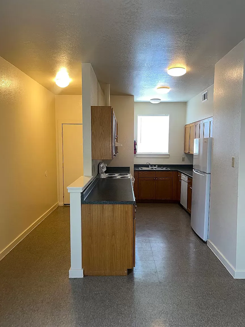 A kitchen with a sink, refrigerator, and cabinets.