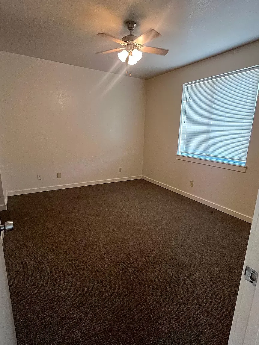 an empty room with a ceiling fan and a window
