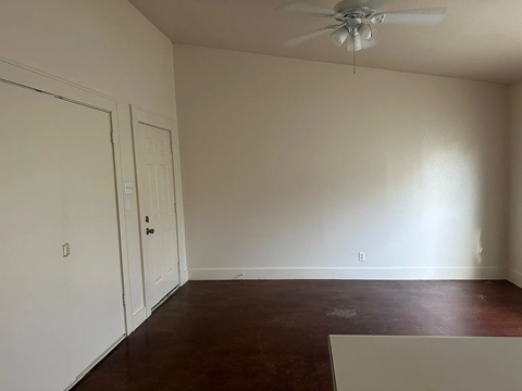 A room with a ceiling fan and two doors.