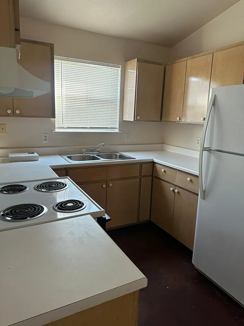 A kitchen with a white stove top oven and a white refrigerator.