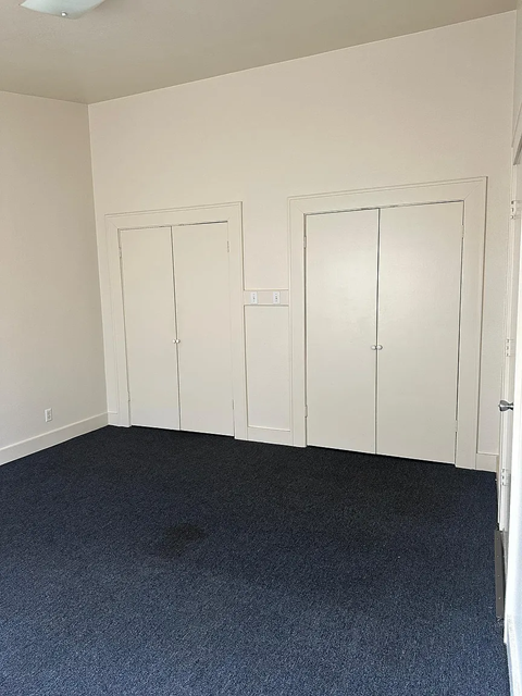 A room with two white doors and a carpeted floor.