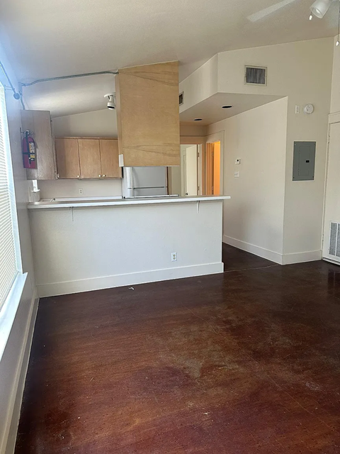 A kitchen area with a white counter and wooden cabinets.