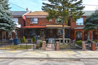 a red brick house with a gate and a tree in front of it