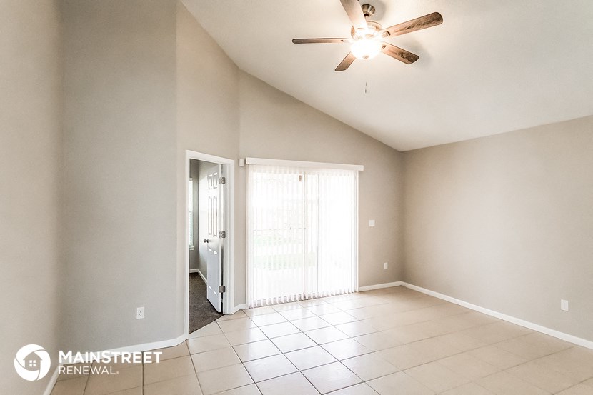 an empty living room with a ceiling fan and a door to a closet