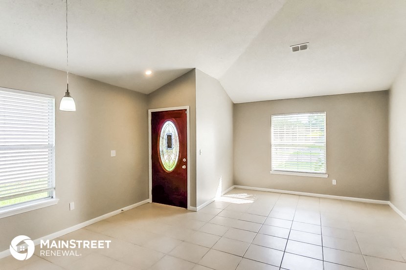 an empty living room with a red door and tiled floors