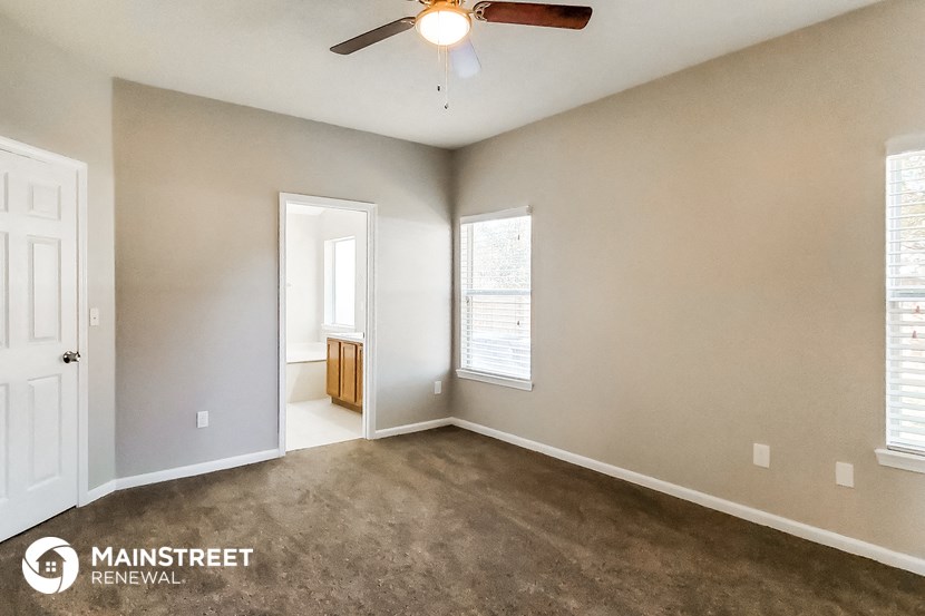 an empty living room with a ceiling fan and a window