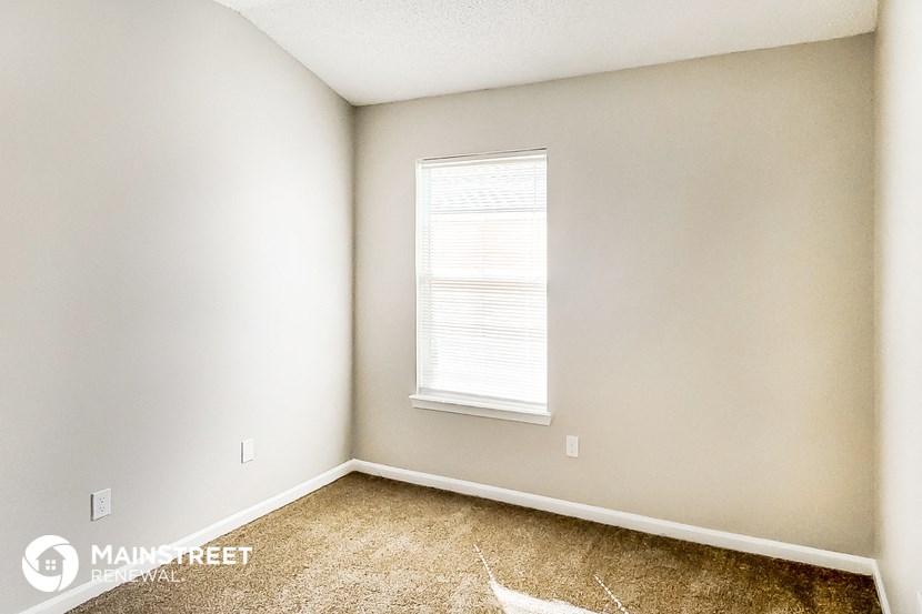 an empty room with a window and carpeting