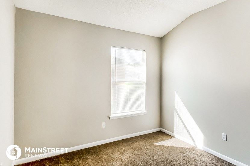 a bedroom with a window and a carpeted floor