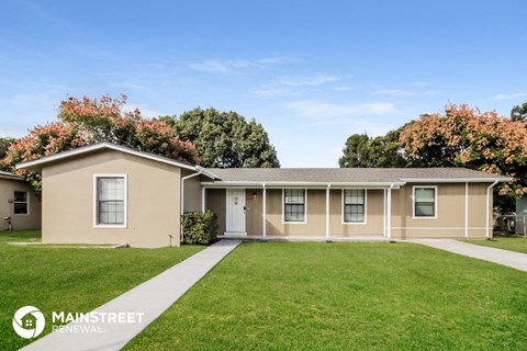 a beige house with a lawn and a sidewalk