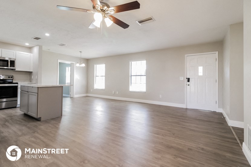 an empty living room and kitchen with a ceiling fan