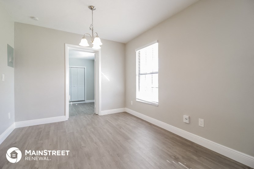 a spacious living room with white walls and wood flooring