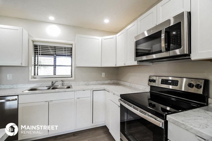 a white kitchen with black appliances and white cabinets