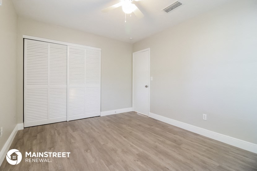 the spacious living room with wood flooring and white walls