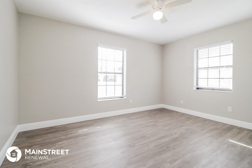 the spacious living room with wood flooring and a ceiling fan